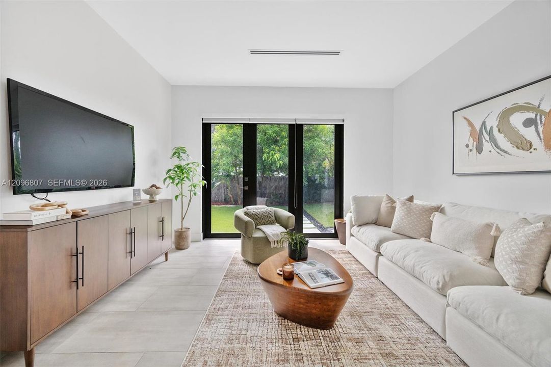 Neutral-toned interior featuring large-format tile flooring, recessed ceiling lighting, and black-framed French doors