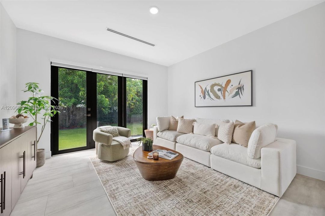 Neutral-toned large-format tile flooring, recessed ceiling lighting, and black-framed glass paneled doors featuring lever hardware