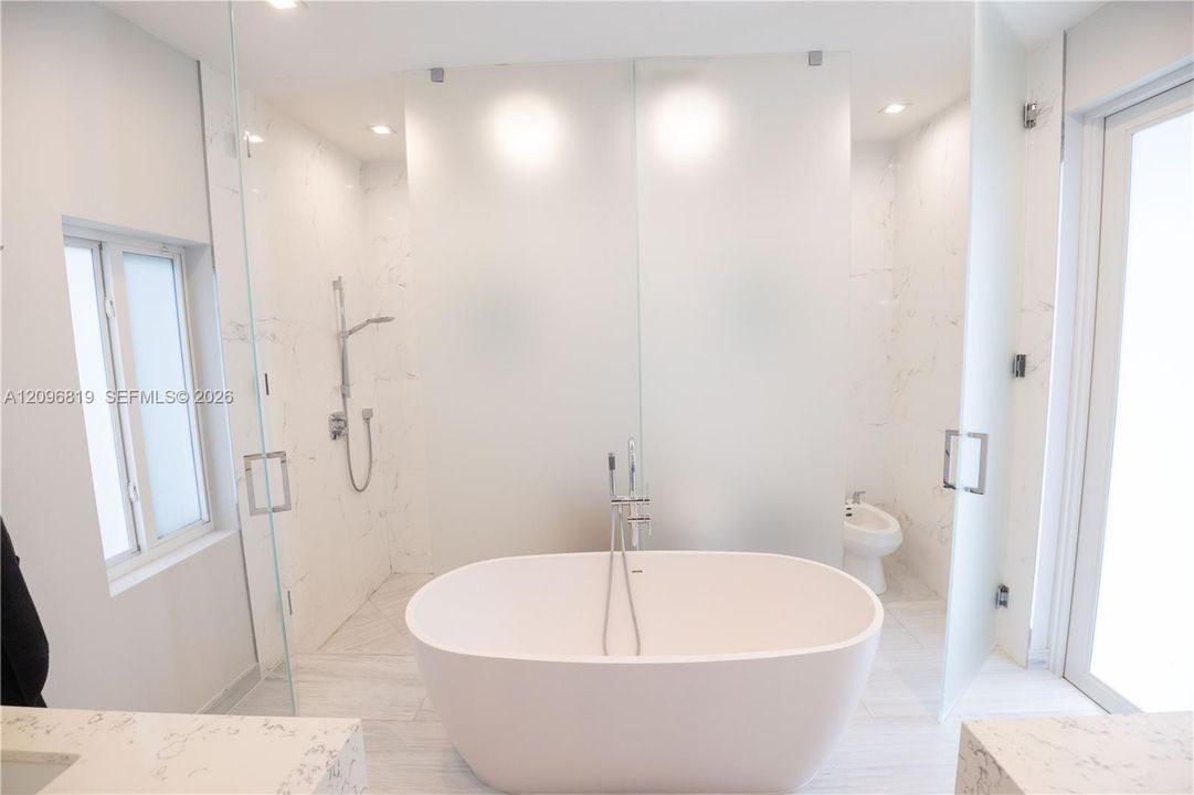 Spa Inspired Primary Bathroom featuring a freestanding stone soaking tub and oversized glass-enclosed walk in shower. And a Private enclosed water closet with toilet and bidet.