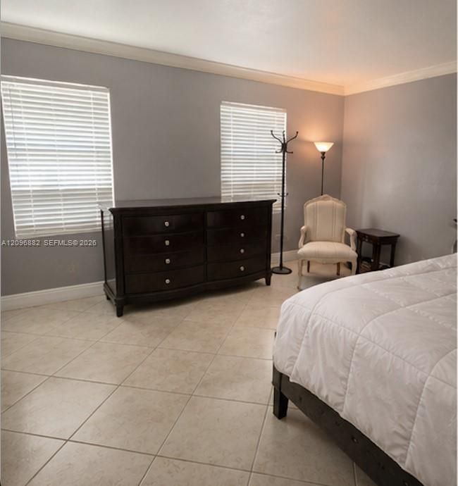 Spacious bedroom featuring tile flooring, crown molding, and multiple windows providing plenty of natural light.