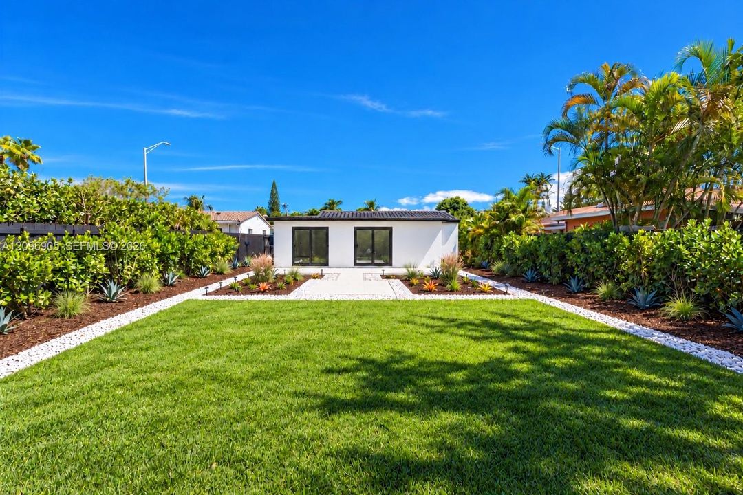 Manicured lawn with white gravel borders, a paver patio, and lush perimeter landscaping