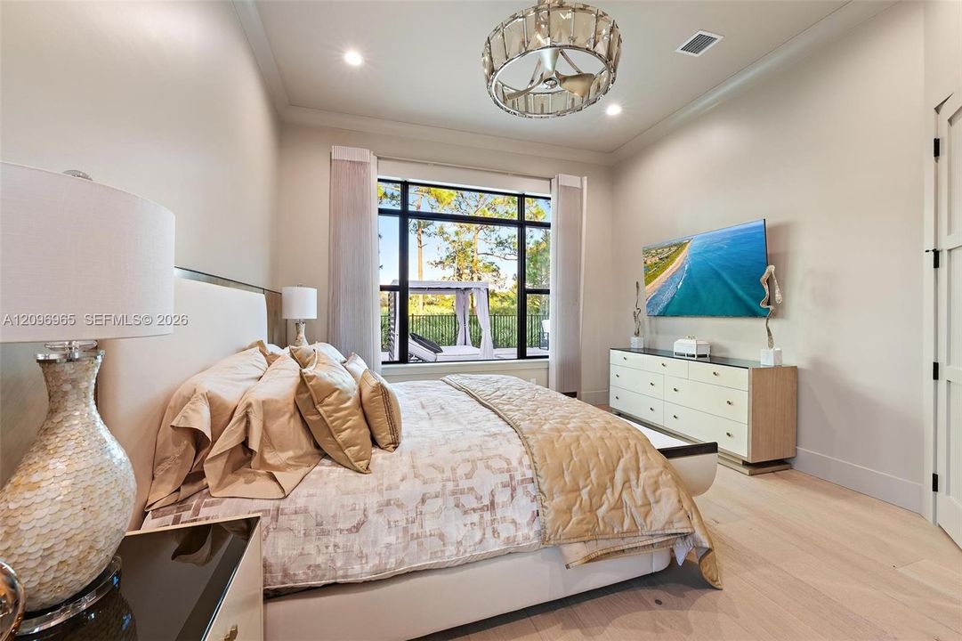 Neutral-toned walls with crown molding, wood-finish flooring, metal-framed windows, and an ornate drum-style ceiling light fixture