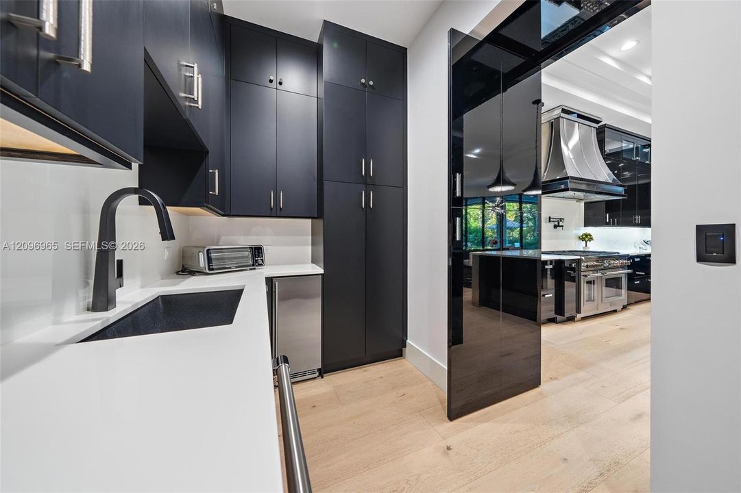 Custom cabinetry in matte finish, quartz countertops, undermount sink with high-arc matte black faucet, and polished black glass sliding door