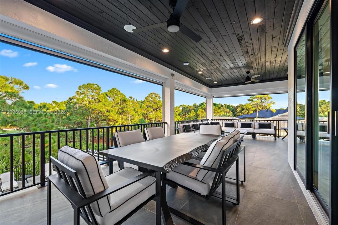 Covered balcony featuring a wood-plank ceiling, recessed lighting, ceiling fans, large-format tile flooring, and black metal railings