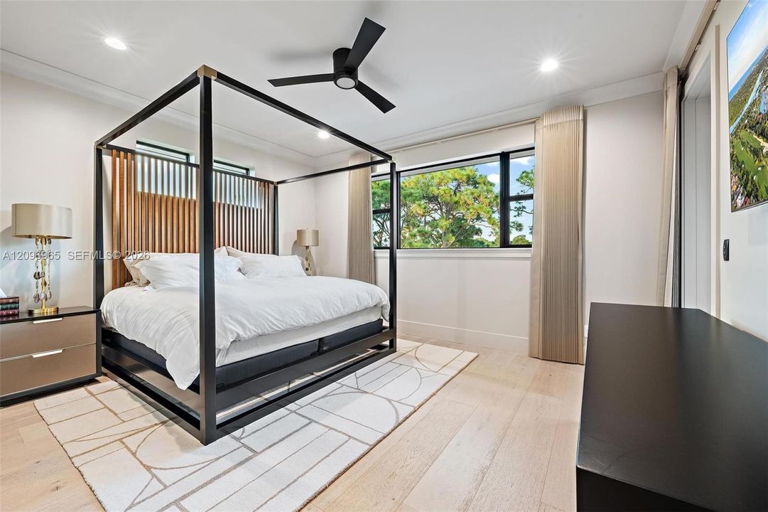Bedroom featuring light-toned wood-finish flooring, recessed lighting, matte black ceiling fan, and large windows with black frames