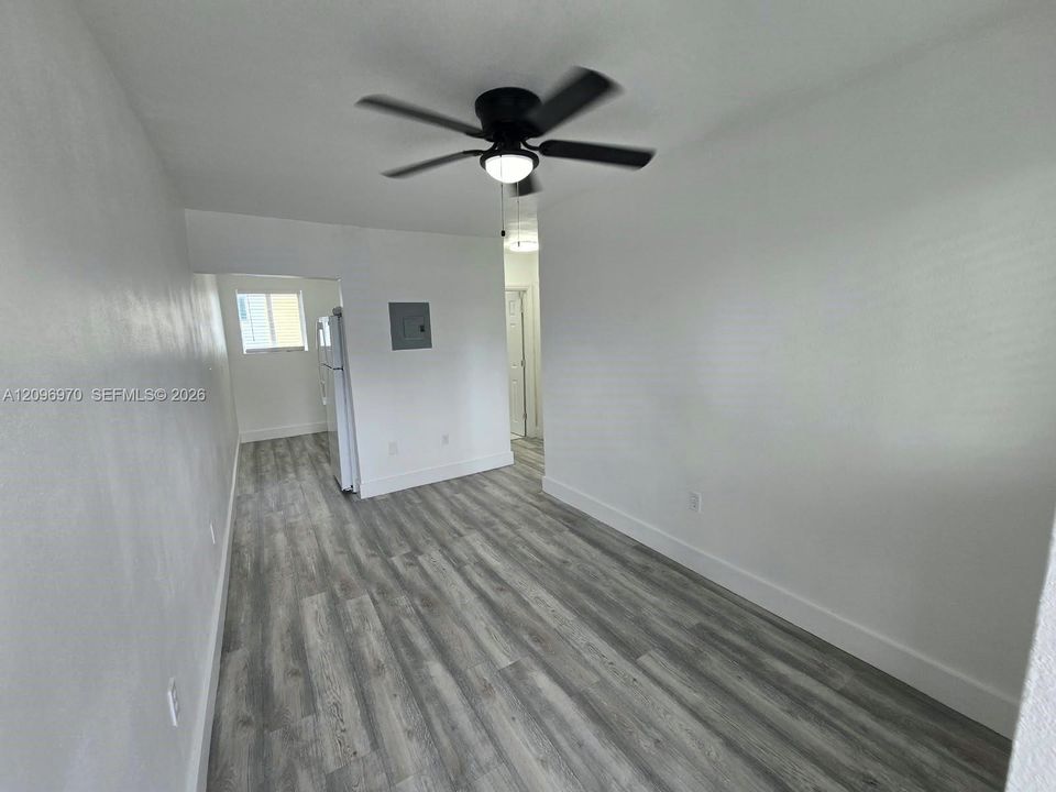 Interior space featuring wood-finish flooring, white walls, and a ceiling fan with integrated lighting