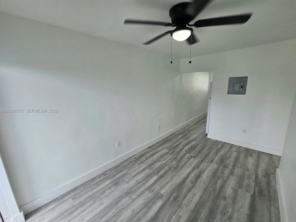 Interior space featuring wood-finish flooring, neutral wall tones, and a ceiling-mounted light fixture with a fan
