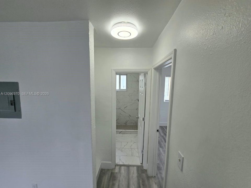 Flush-mount LED ceiling lighting, wood-finish flooring, and a bathroom featuring large-format tile flooring and wall surfacing