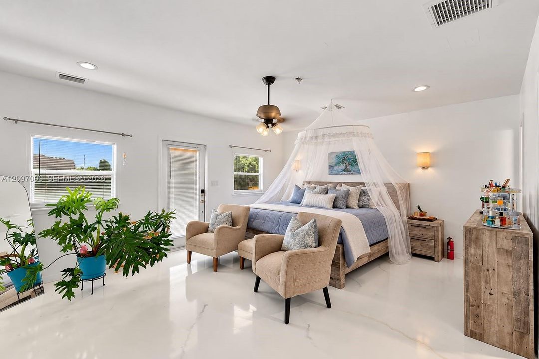 Spacious room featuring high ceilings, recessed lighting, polished stone-finish flooring, a central multi-light ceiling fan, and direct exterior access
