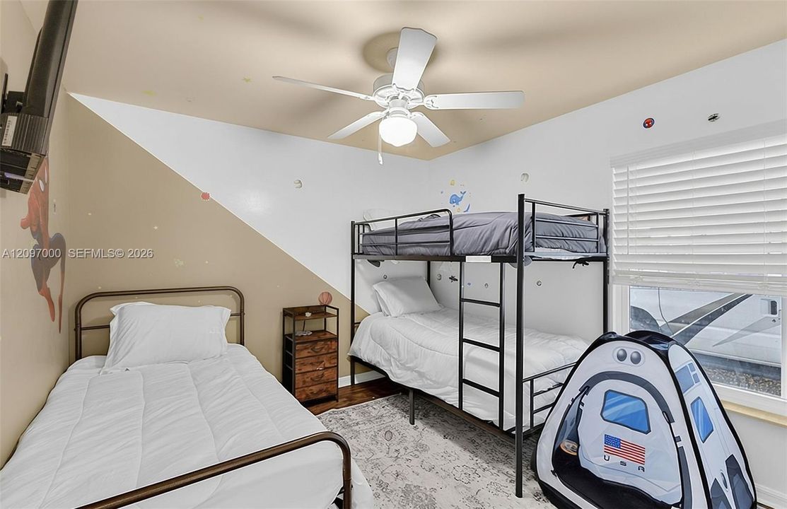 Interior room featuring a ceiling fan, horizontal slat window blinds, and wood-finish flooring