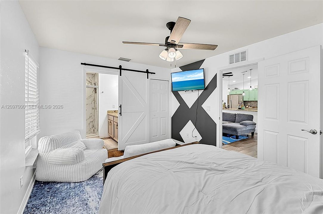 White barn-style sliding door, ceiling fan with integrated lighting, neutral wall finishes, and paneled doors
