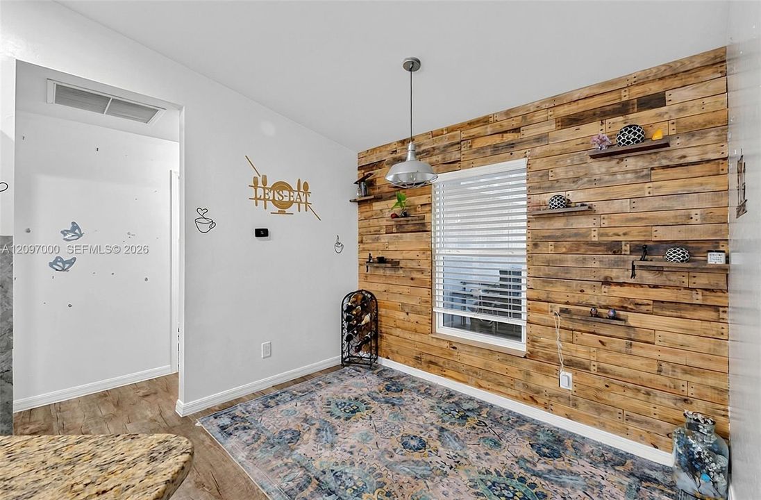 Accent wall featuring reclaimed wood paneling, integrated floating wood shelving, a central window with horizontal blinds, and a suspended industrial-style pendant light fixture
