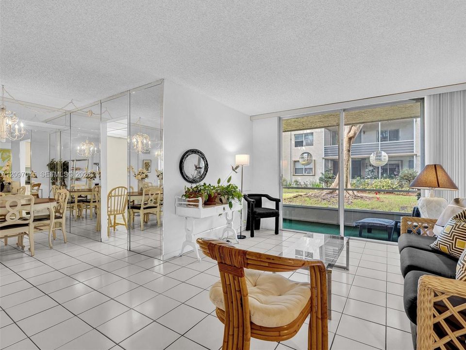 Open-concept living space featuring white floor tiles, floor-to-ceiling mirrored walls, and expansive sliding glass doors