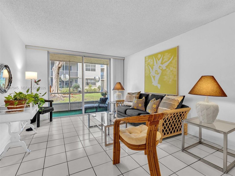 Living area featuring large-format ceramic tile flooring and floor-to-ceiling sliding glass doors opening to a screened balcony