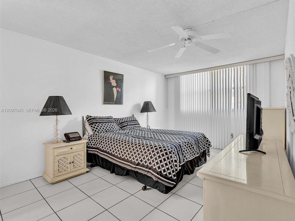 Room featuring white tile flooring, white vertical window blinds, and a white ceiling fan with integrated lighting