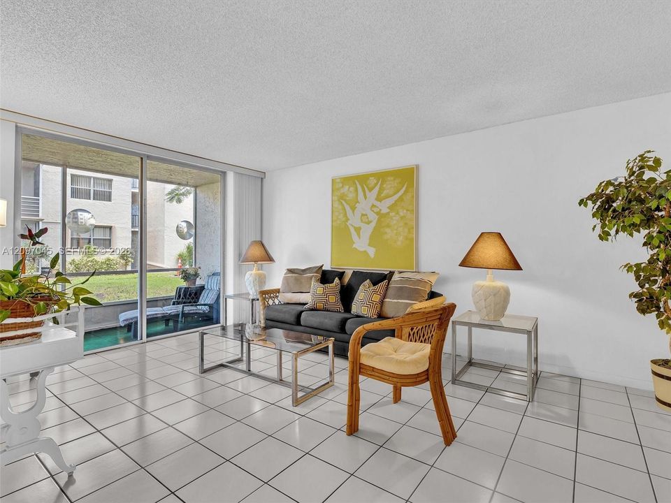 Living area featuring large-format ceramic tile flooring and floor-to-ceiling sliding glass doors opening to a covered patio