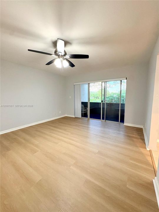 Wood-finish flooring, ceiling fan with integrated lighting, and sliding glass doors with vertical blinds