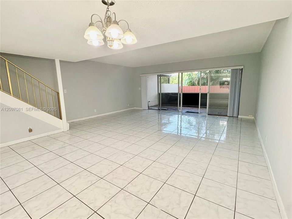 Open floor plan featuring large-format tile flooring, a multi-pane glass sliding door, and a multi-arm chandelier with brushed-metal finish