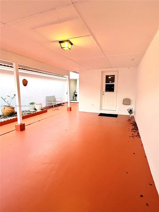 Covered patio featuring a solid-surface floor, recessed lighting, and a garden bed bordered by decorative stone
