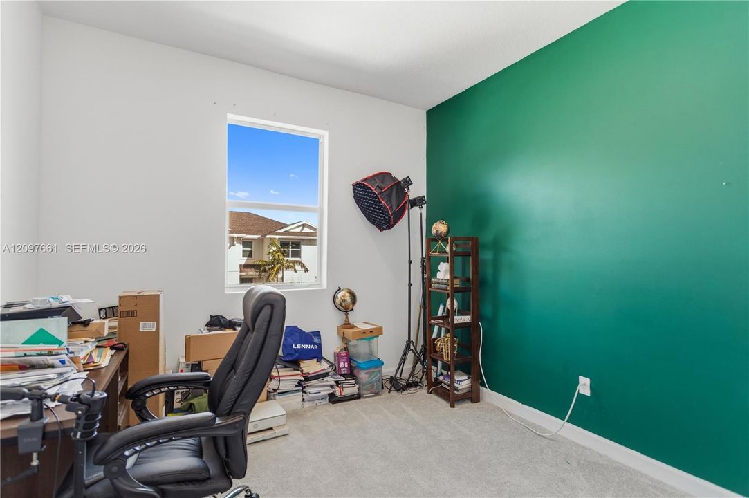 Room featuring a vibrant green accent wall, neutral carpeting, and a large window providing natural light