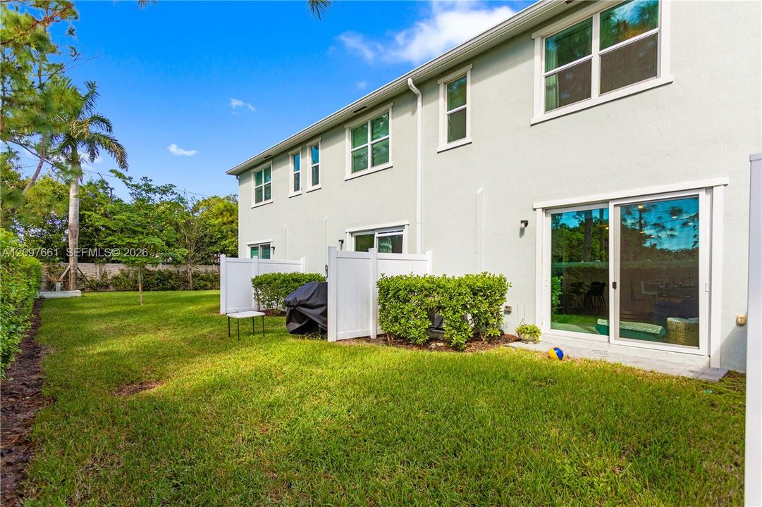Stucco exterior featuring dual-pane windows, sliding glass door, and a private rear yard with vinyl privacy fencing
