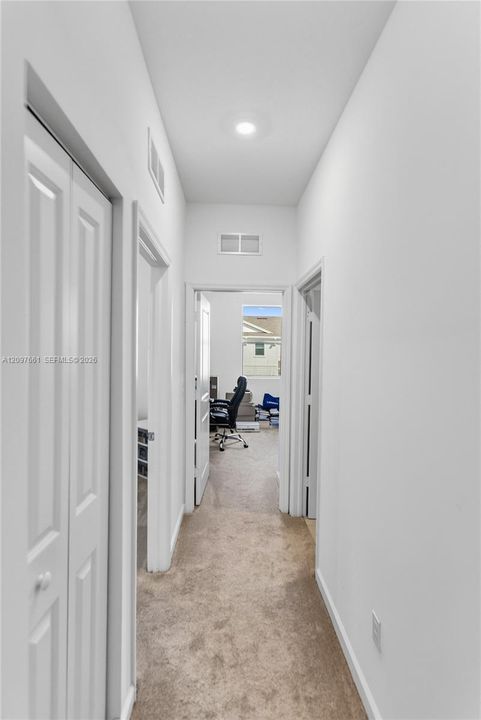 Hallway featuring neutral carpeting, recessed ceiling lighting, and multiple interior doorways with white bi-fold closet doors