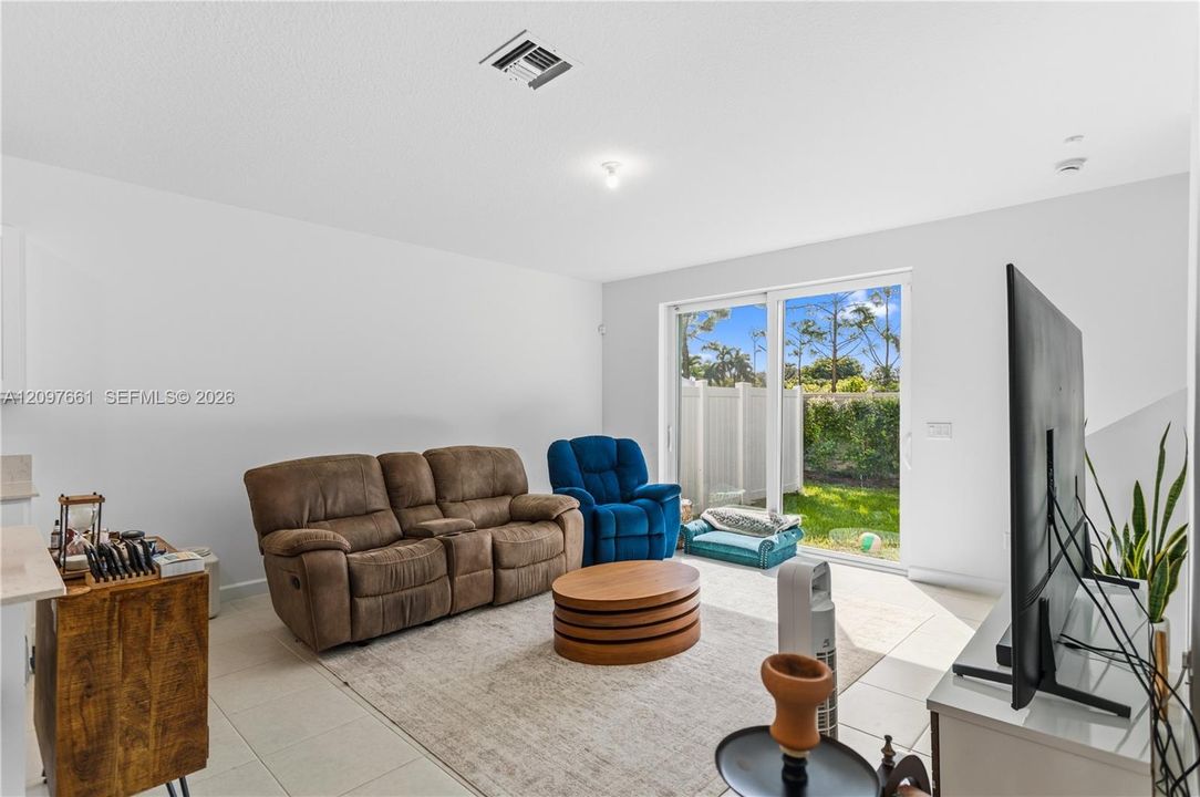 Neutral-toned ceramic tile flooring, sliding glass door, and exterior access to a fenced rear yard