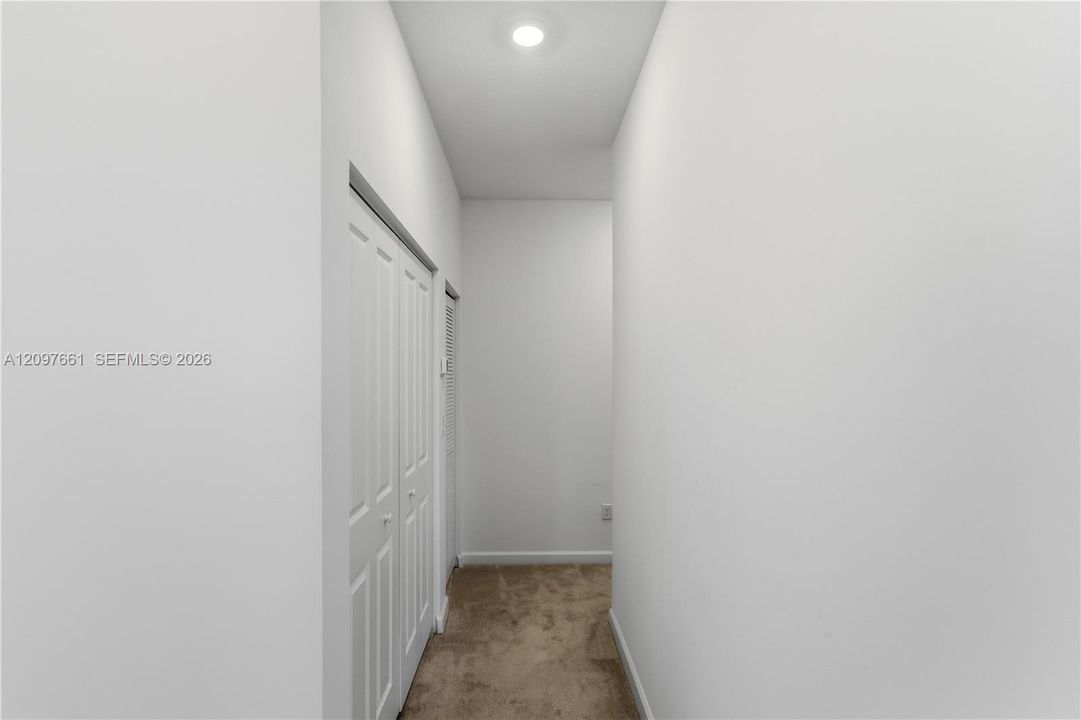 Neutral-toned interior hall featuring wall-to-wall carpeting, recessed ceiling lighting, and double-door closet storage