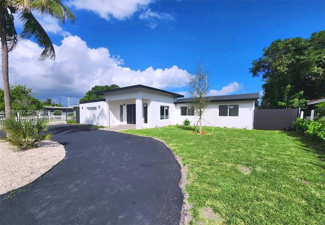 Single-story residence featuring a smooth stucco exterior, flat roofline, asphalt driveway, manicured lawn, and attached garage