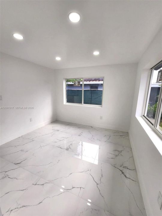Polished stone-finish tile flooring, recessed ceiling lighting, and large-format sliding windows