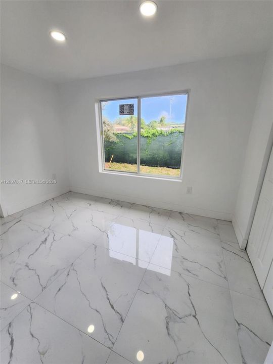 Large-format stone-finish floor tiles featuring veined detailing, recessed ceiling lighting, and a large horizontal sliding window