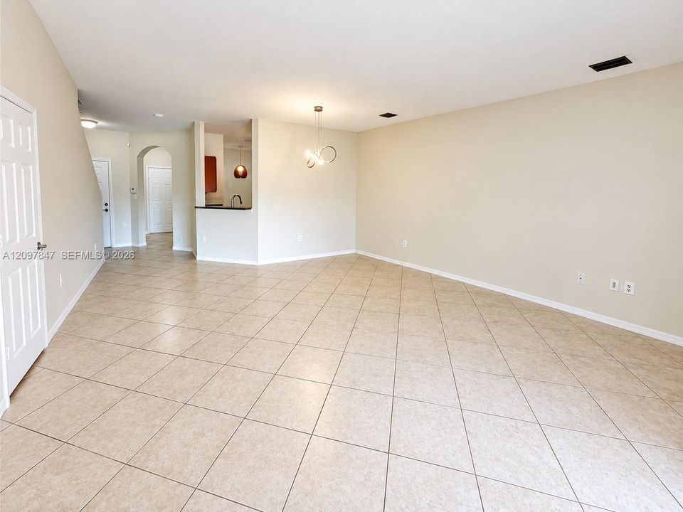 Neutral-toned tile flooring throughout, arched entryway, and contemporary multi-pendant lighting fixture