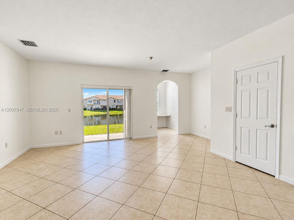 Neutral tile flooring, sliding glass patio door, arched architectural opening, and interior six-panel door