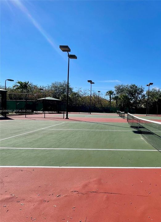 Multi-court tennis facility featuring hard-surface playing areas, perimeter fencing, and overhead court lighting