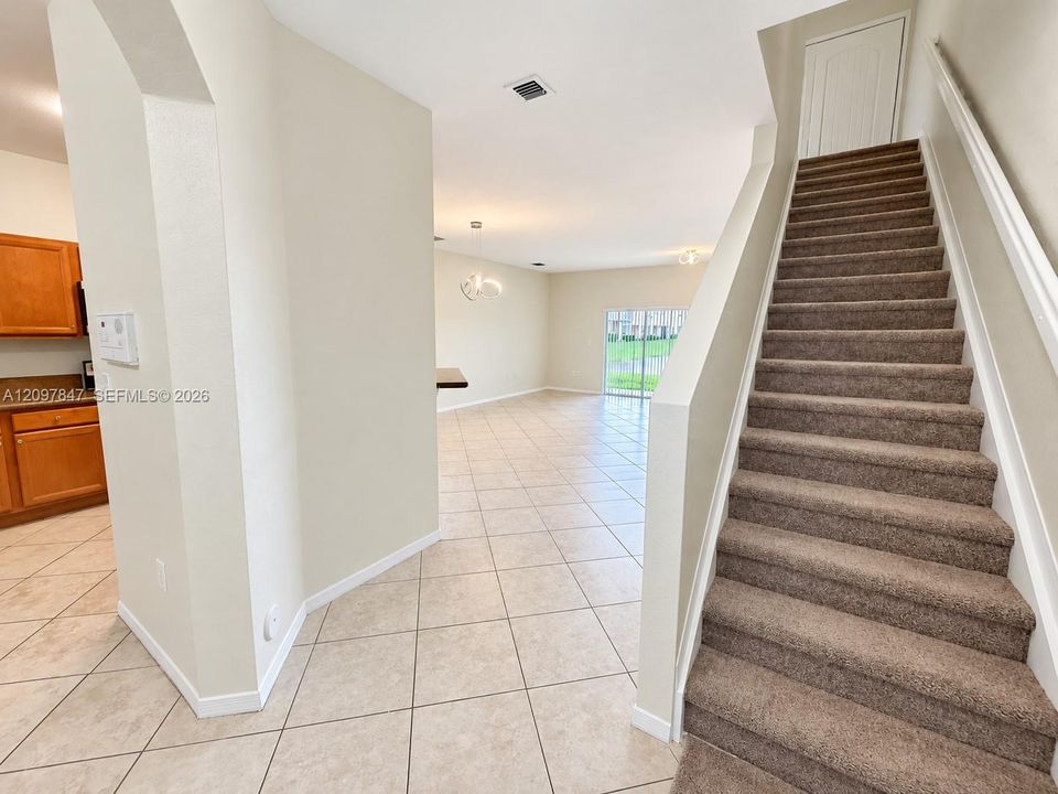 Carpeted staircase with white balustrade, neutral tile flooring, and sliding glass doors
