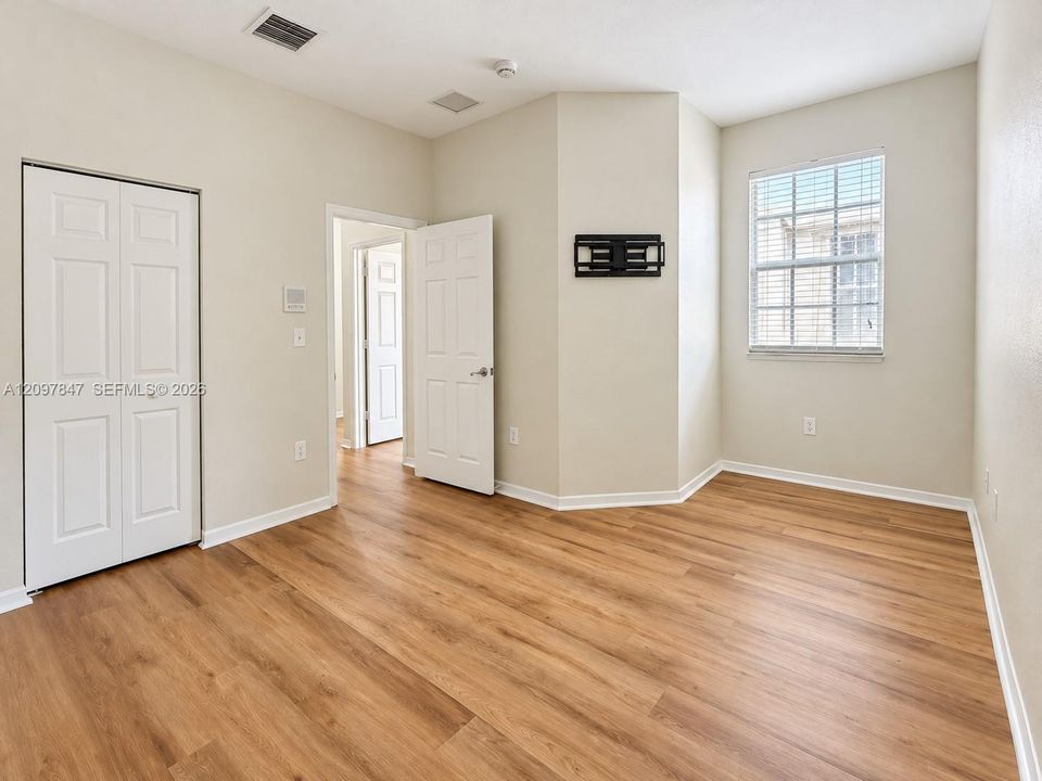 Wood-finish flooring, neutral wall tones, multi-panel doors, and a double-door closet