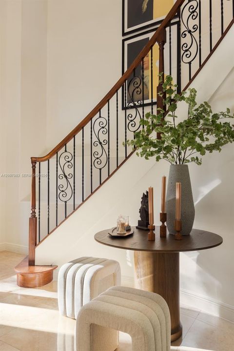 Staircase featuring a decorative wrought iron railing with scrollwork detailing and a smooth wood-finished handrail terminating in a curved starter step