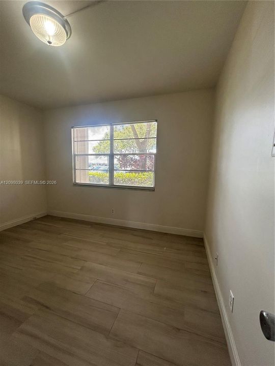 Neutral-toned room featuring wood-finish flooring, a flush-mount dome light fixture, and horizontal sliding window