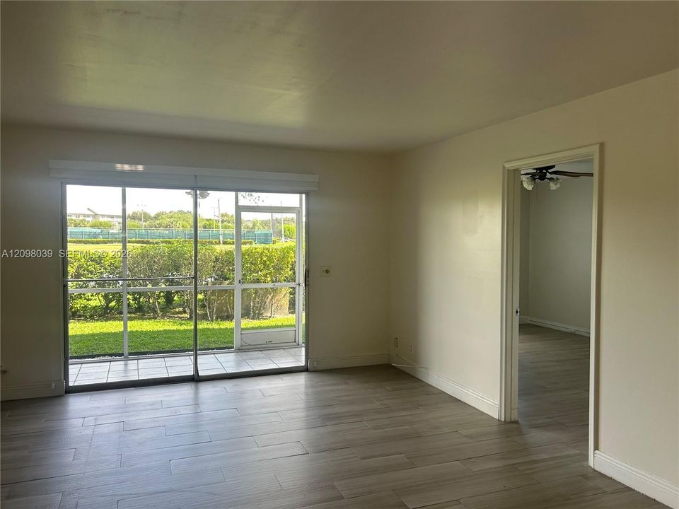 Wood-finish tile flooring, large sliding glass door with integrated screen, and a screened-in tiled patio