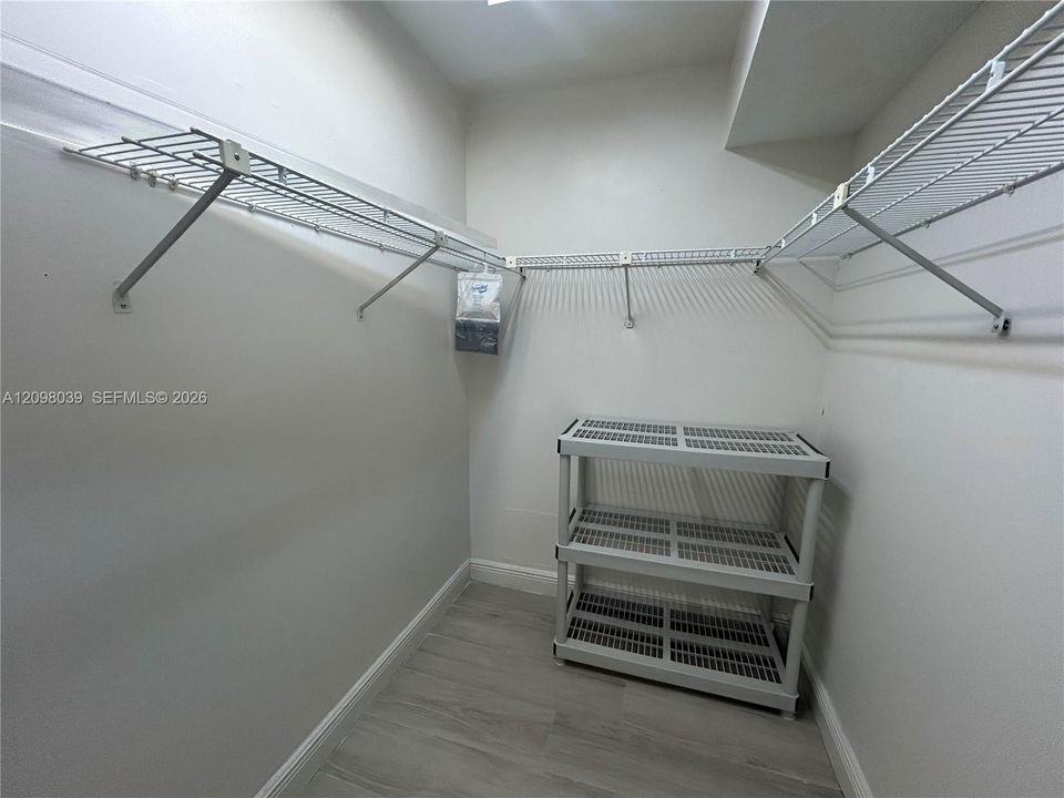 Walk-in closet featuring light wood-finish flooring and tiered wire shelving