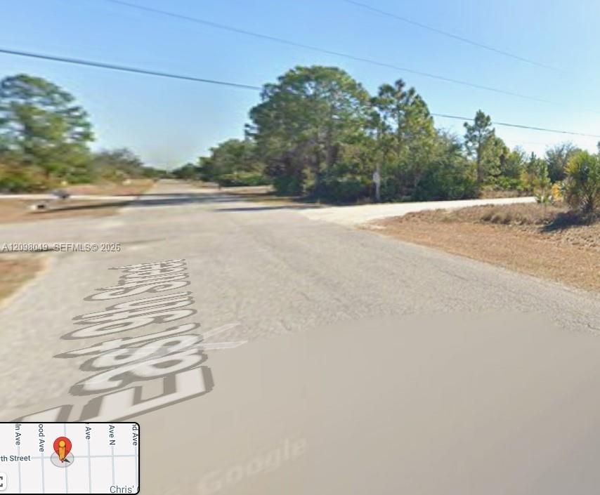 Corner lot featuring paved road access, cleared land, and established mature trees