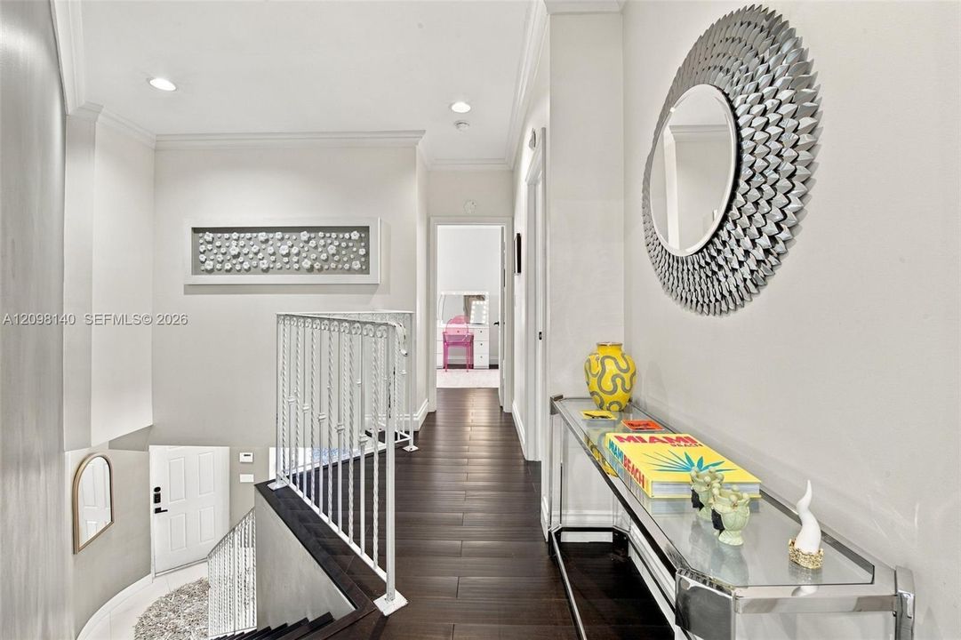 Hallway featuring dark wood-finish flooring, recessed lighting, and white ornamental stair railing