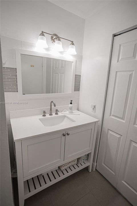 White vanity with an open lower shelf and modern lighting.