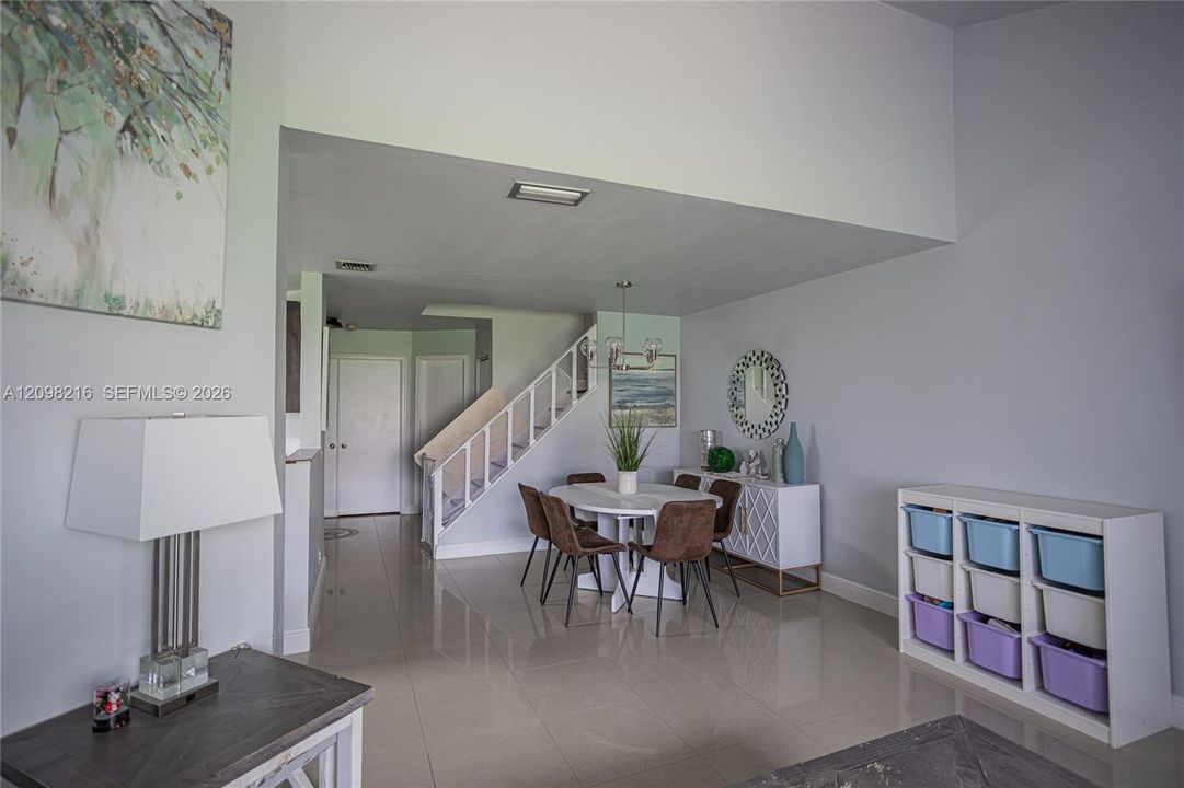 Open dining and living layout under dramatic two story ceiling volume.
