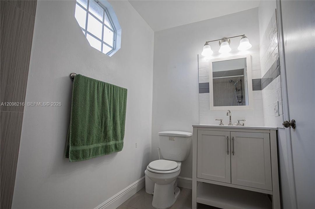 Bathroom with a crisp white vanity and a round accent window.