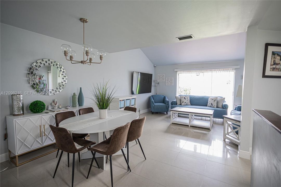 Dining area with a statement chandelier, open to the living room.