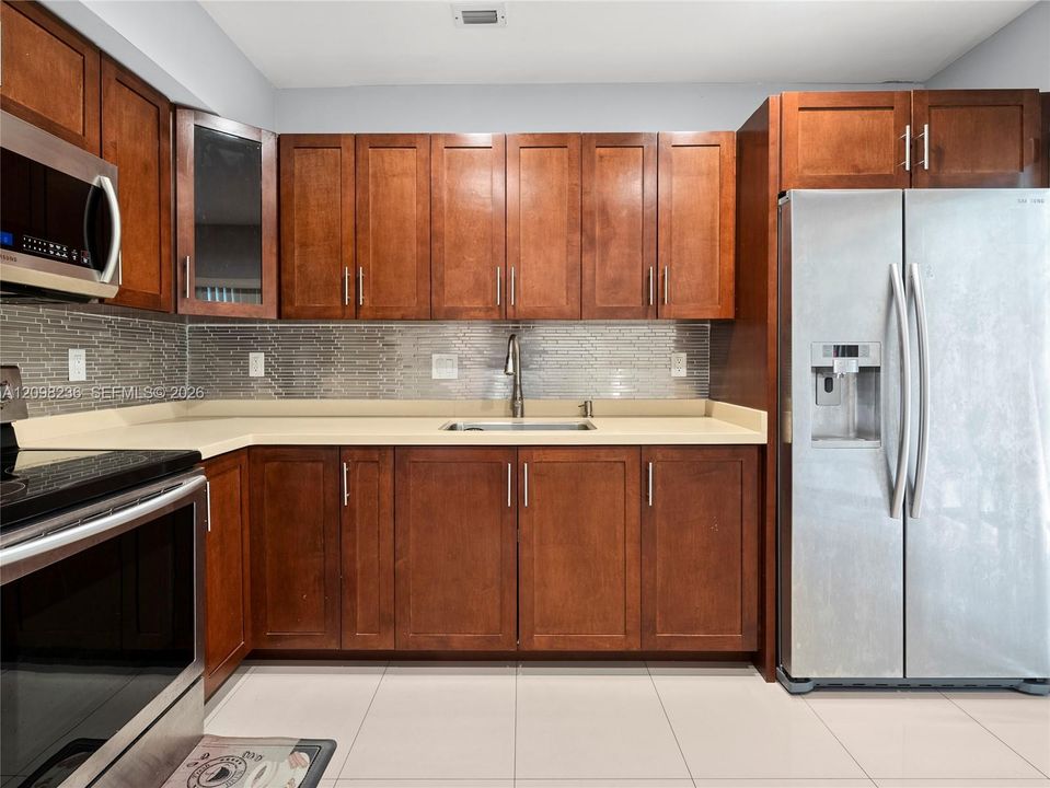Updated kitchen featuring stainless-steel appliances, abundant cabinetry, and decorative backsplash.