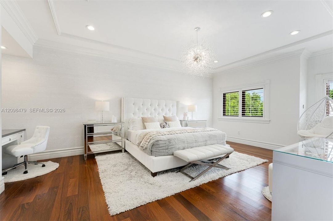 Recessed lighting, crown molding, wood-finish flooring, white window shutters, and a crystal chandelier