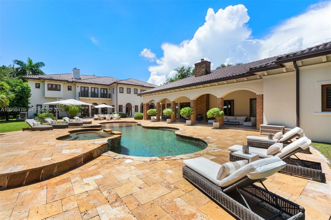 Resort-style backyard featuring a freeform swimming pool, integrated spa, and expansive paver patio
