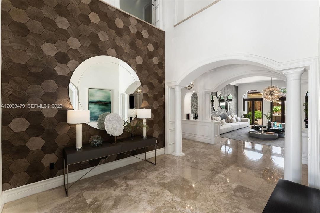 Hexagonal accent wall, polished stone flooring, arched doorways, interior columns, and a double-height ceiling